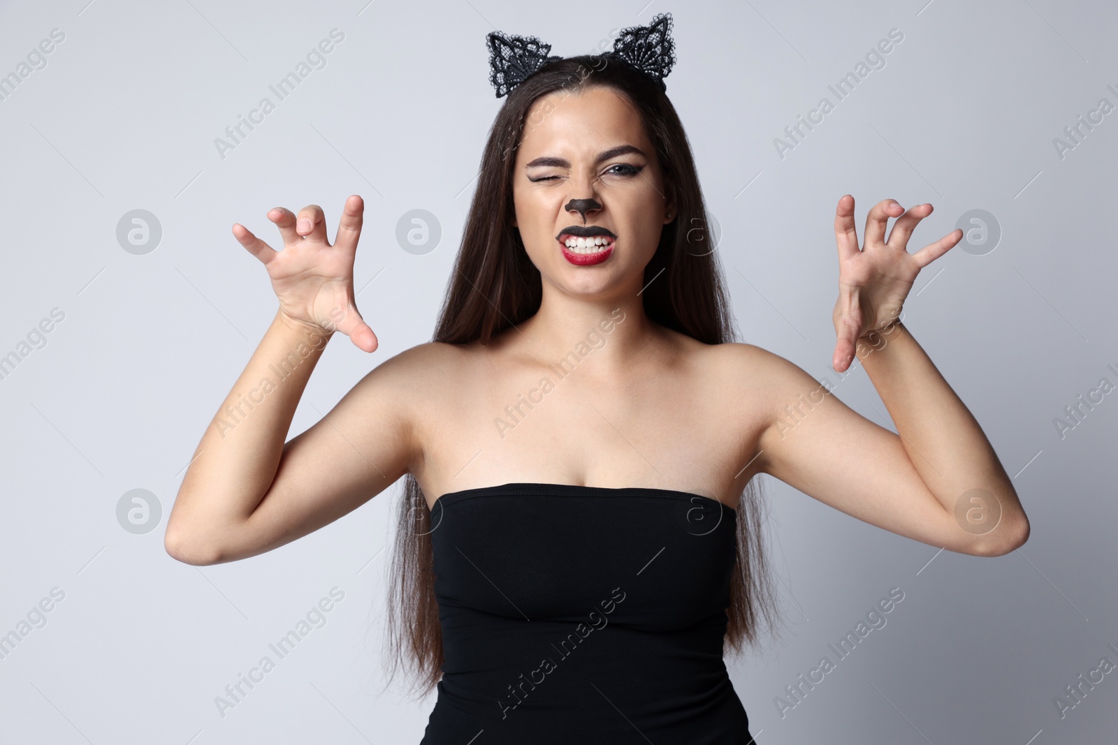 Photo of Playful woman with cat makeup and ears on white background