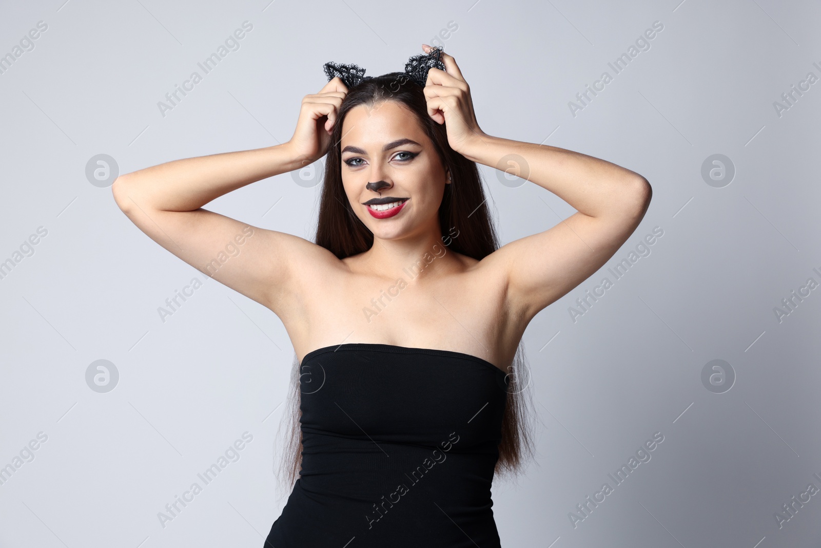 Photo of Smiling woman with cat makeup and ears on white background