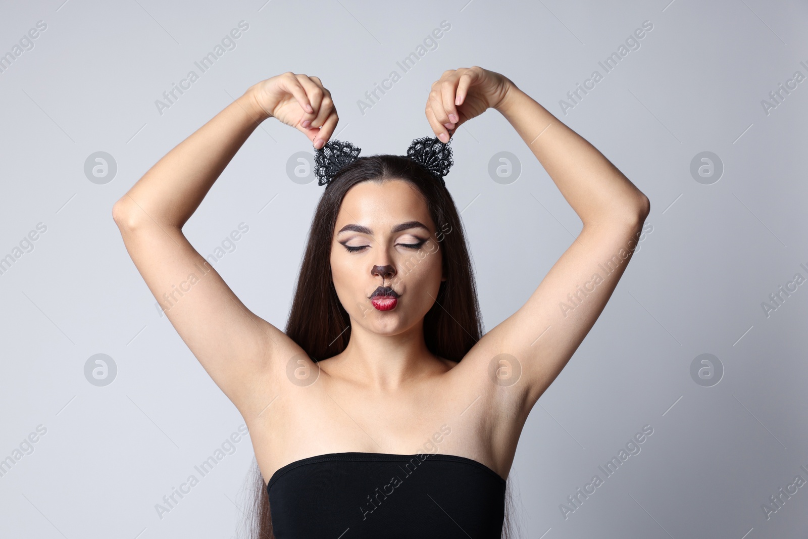 Photo of Playful woman with cat makeup and ears on white background