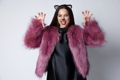 Photo of Playful woman with cat makeup and ears on white background