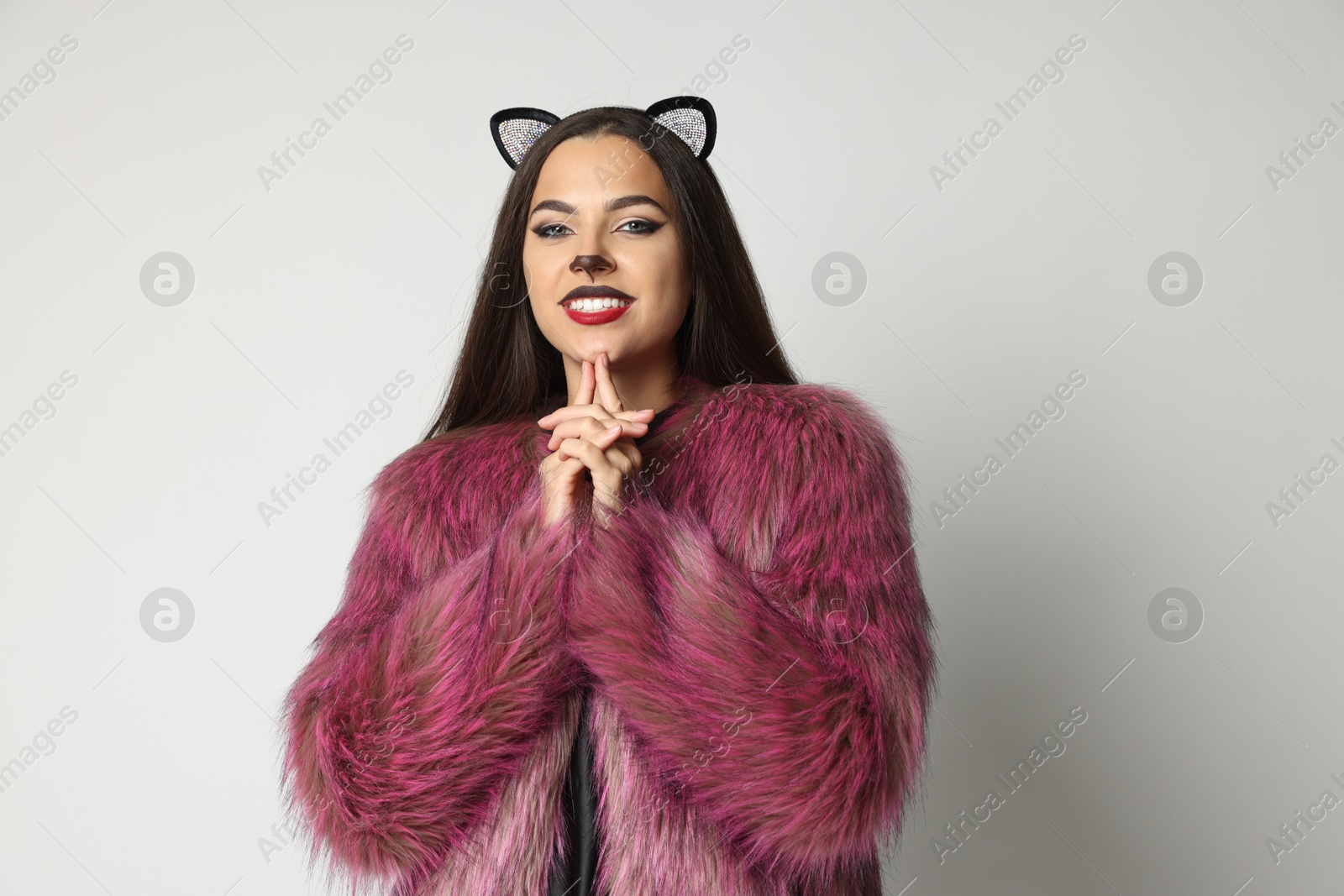 Photo of Smiling woman with cat makeup and ears on white background