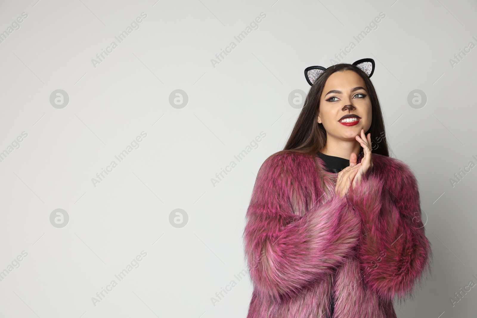 Photo of Smiling woman with cat makeup and ears on white background. Space for text