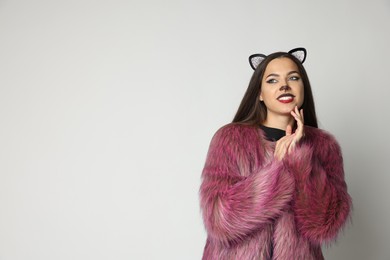 Photo of Smiling woman with cat makeup and ears on white background. Space for text