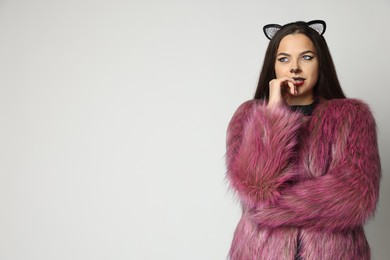 Photo of Attractive woman with cat makeup and ears on white background. Space for text