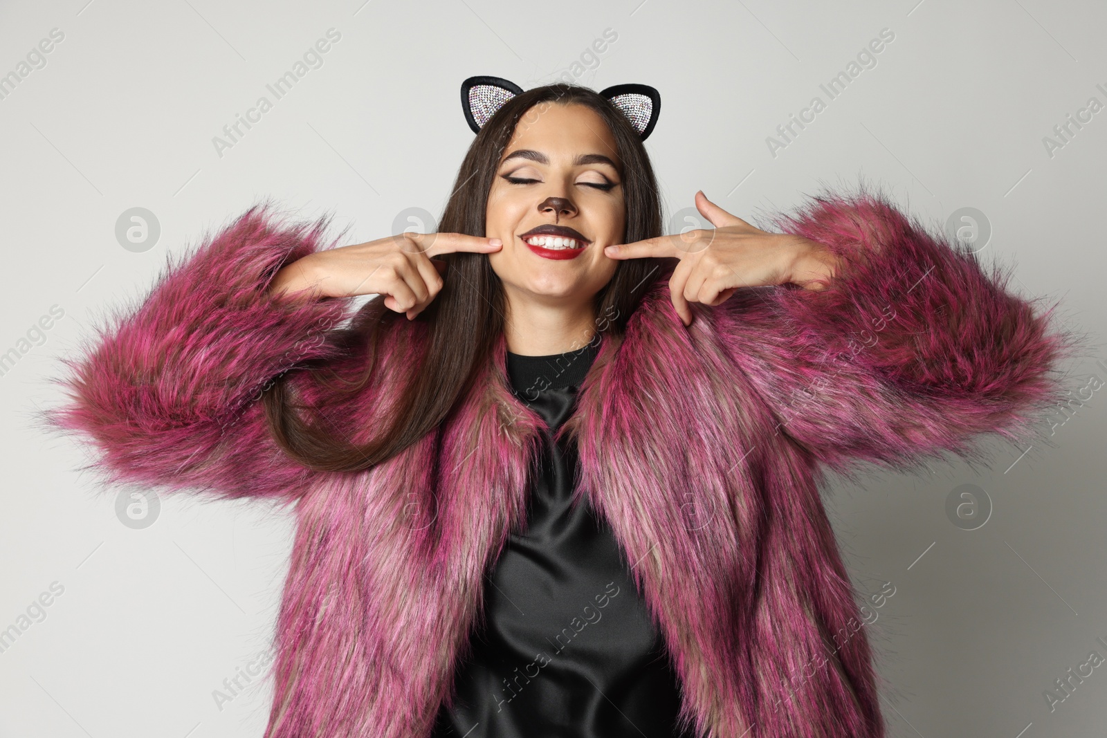 Photo of Smiling woman with cat makeup and ears on white background