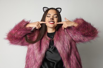 Photo of Smiling woman with cat makeup and ears on white background