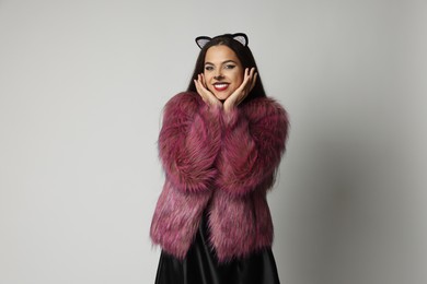 Photo of Smiling woman with cat makeup and ears on white background