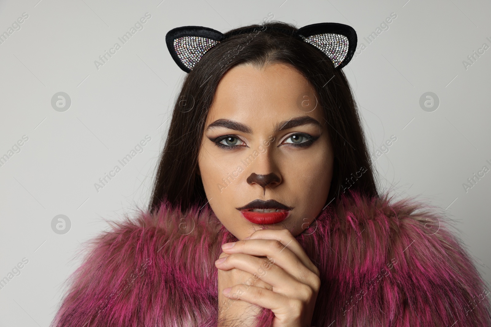 Photo of Attractive woman with cat makeup and ears on white background