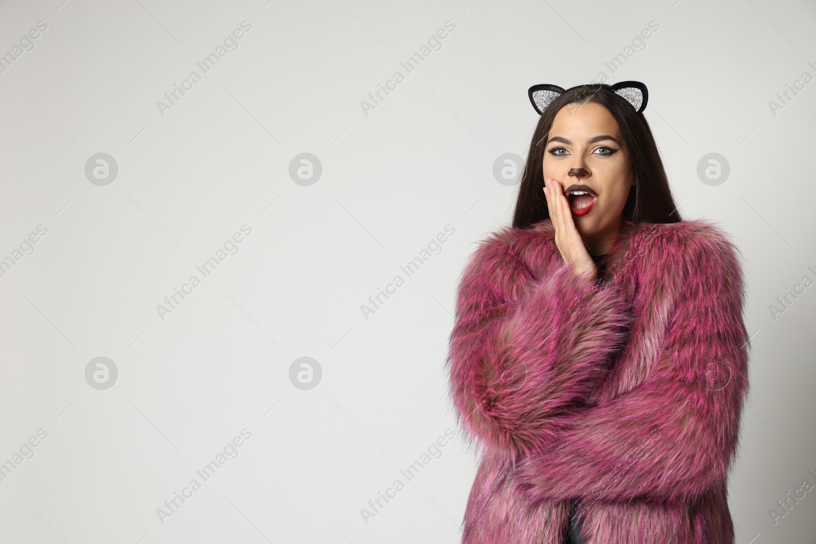 Photo of Emotional woman with cat makeup and ears on white background. Space for text