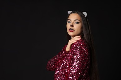 Photo of Charming woman with cat makeup and ears on black background