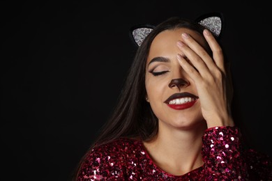 Photo of Charming woman with cat makeup and ears on black background. Space for text