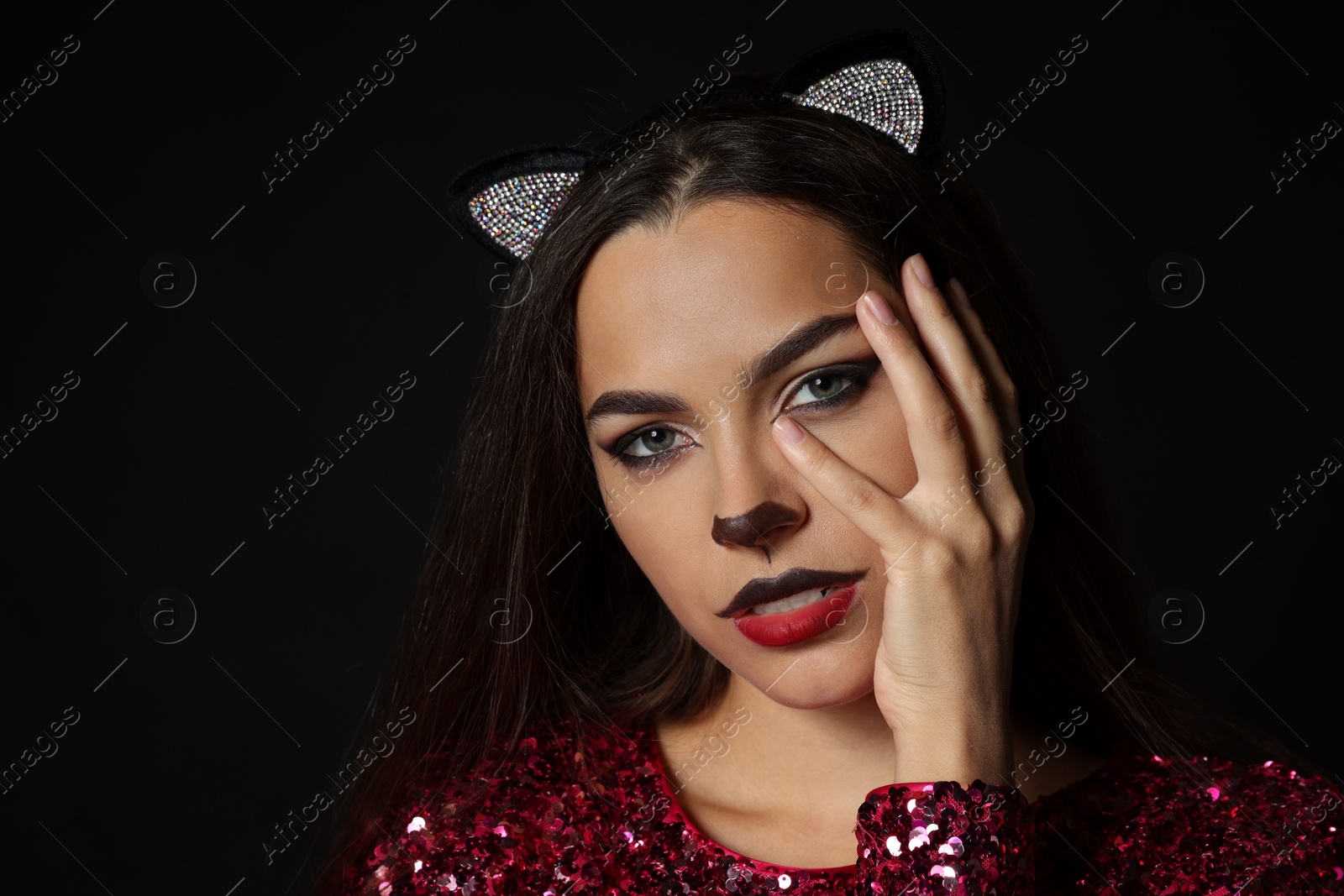 Photo of Charming woman with cat makeup and ears on black background