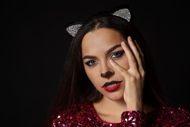 Photo of Charming woman with cat makeup and ears on black background