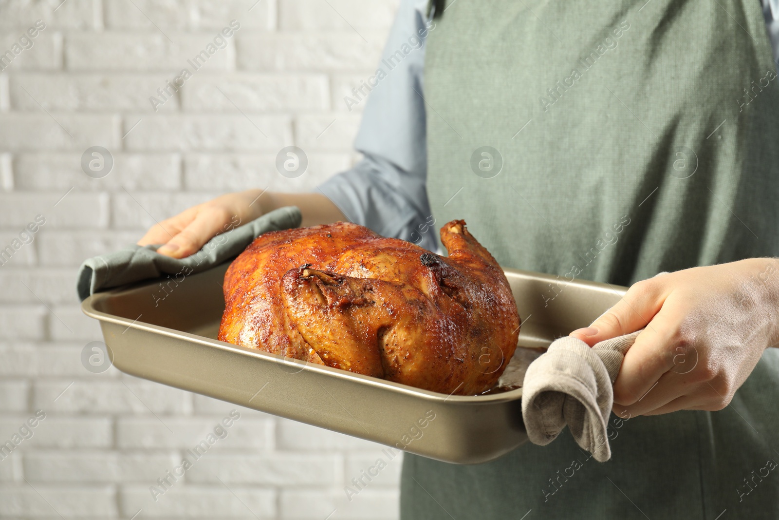 Photo of Woman holding baking tray with delicious baked turkey indoors, closeup