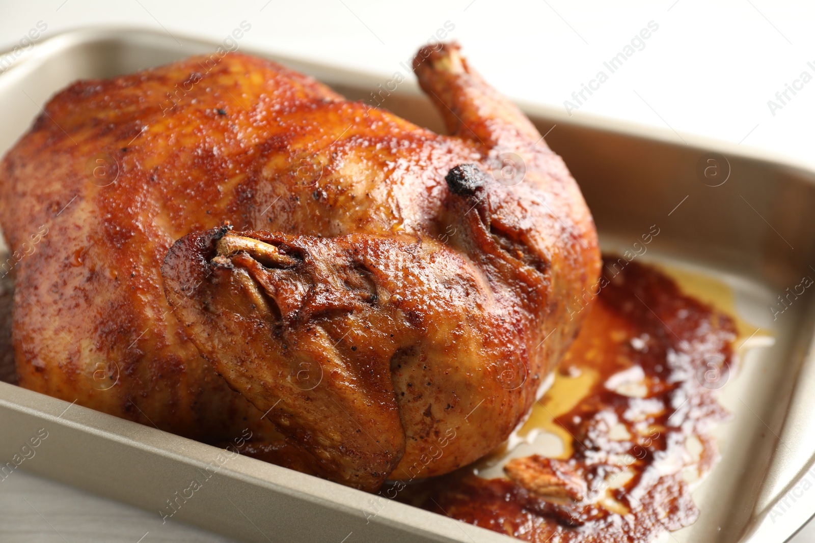 Photo of Delicious baked turkey in baking dish on light table, closeup