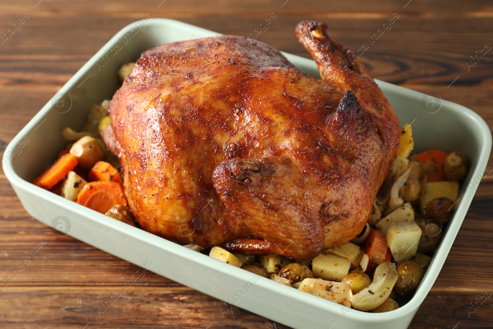 Photo of Delicious baked turkey and vegetables in baking dish on wooden table, closeup