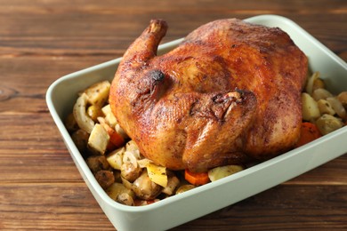 Photo of Delicious baked turkey and vegetables in baking dish on wooden table, closeup