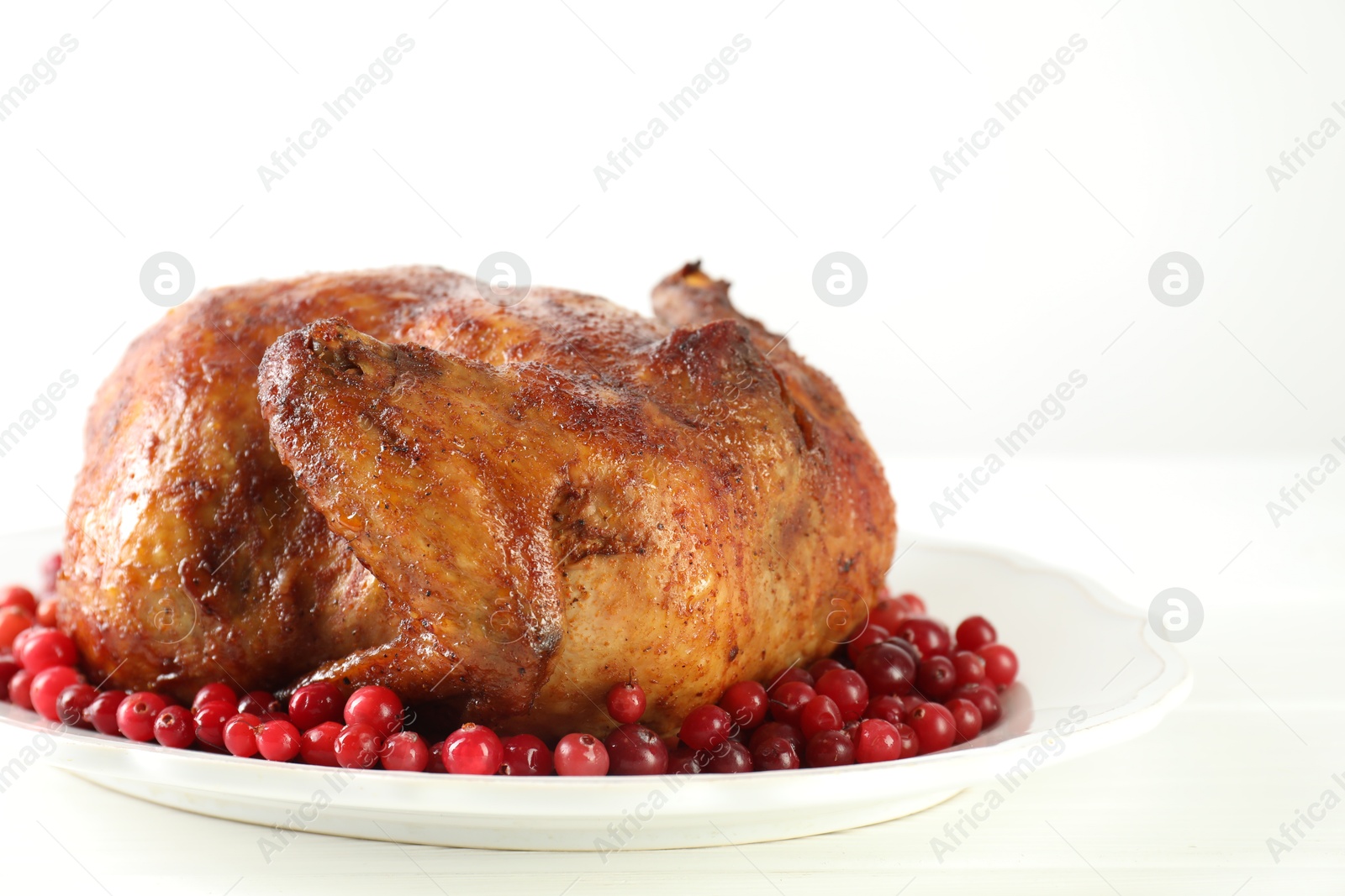 Photo of Delicious baked turkey and cranberries on white wooden table, closeup. Space for text