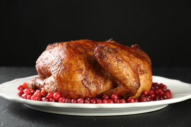 Delicious baked turkey and cranberries on dark gray textured table against black background, closeup