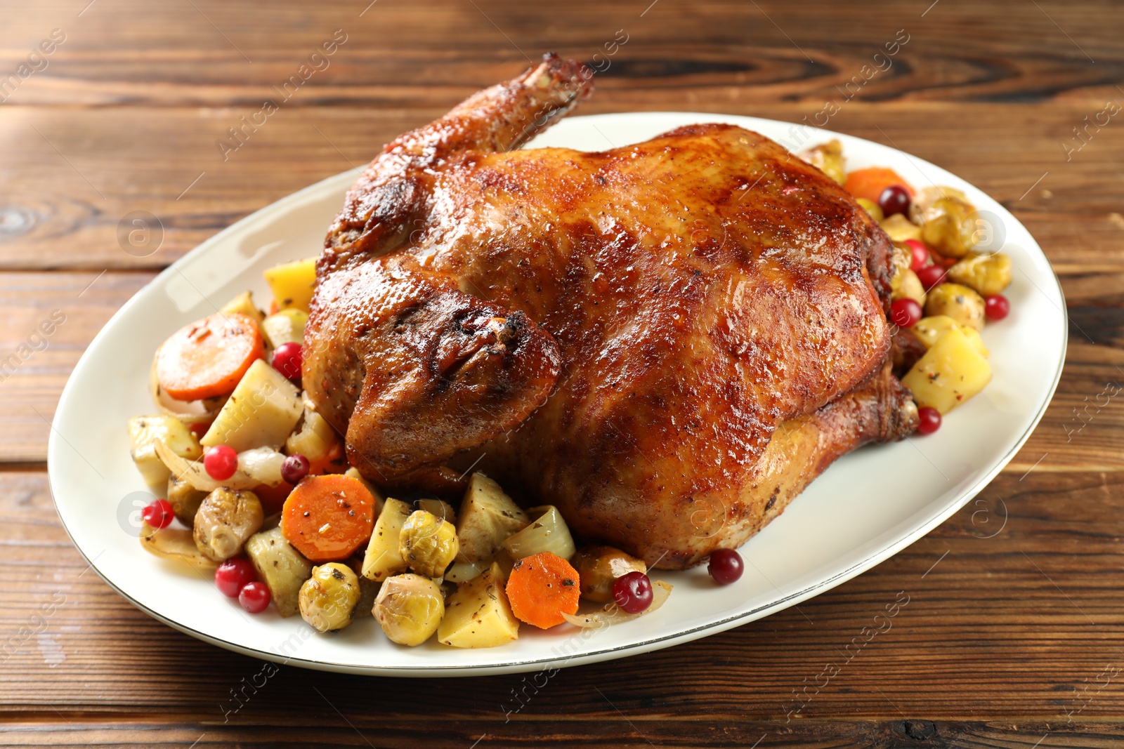 Photo of Delicious baked turkey, vegetables and cranberries on wooden table, closeup