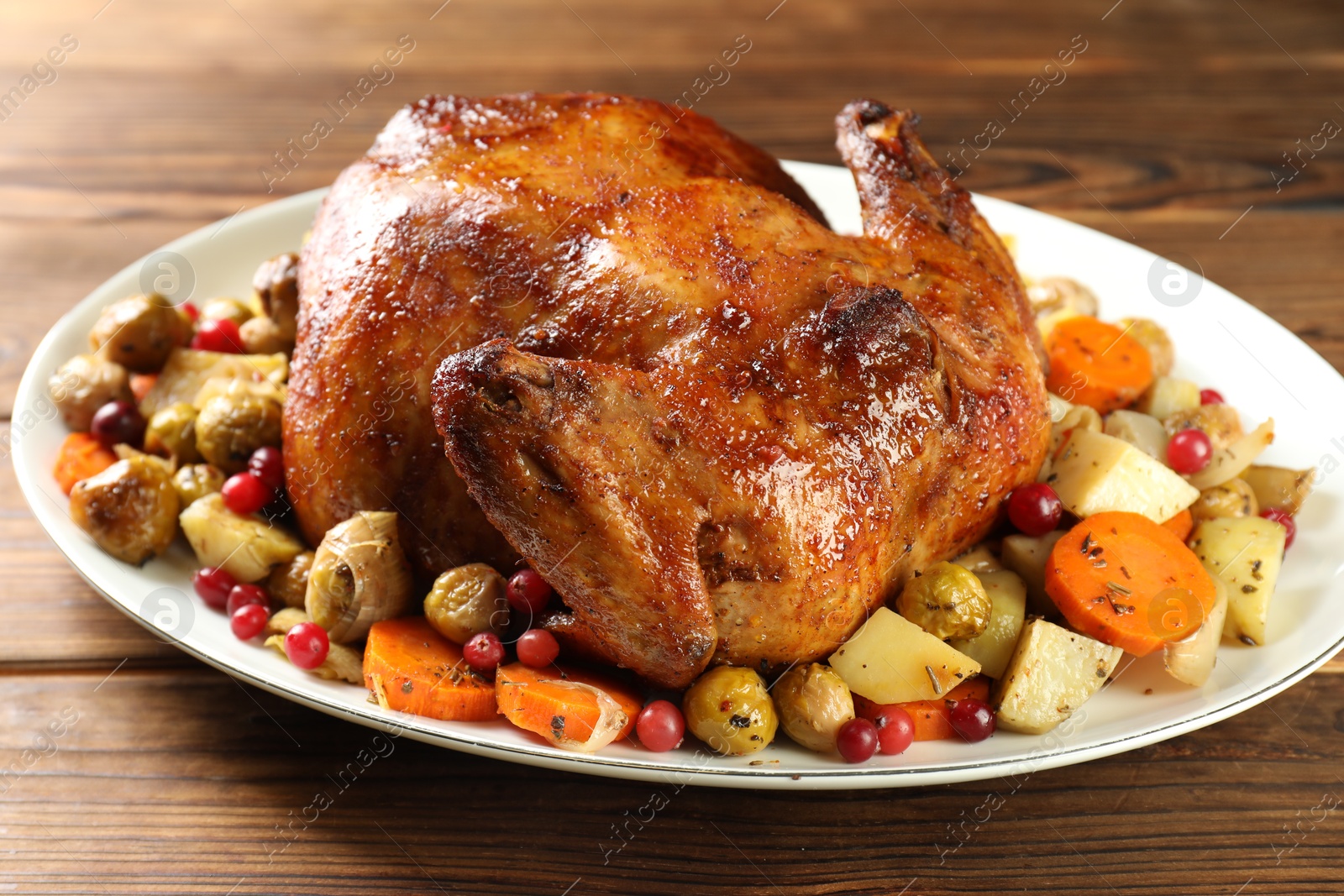 Photo of Delicious baked turkey, vegetables and cranberries on wooden table, closeup