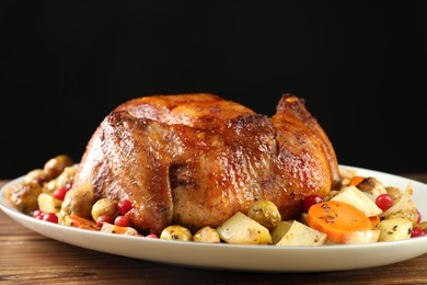 Photo of Delicious baked turkey, vegetables and cranberries on wooden table against black background, closeup