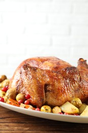 Photo of Delicious baked turkey, vegetables and cranberries on wooden table against white brick wall, space for text