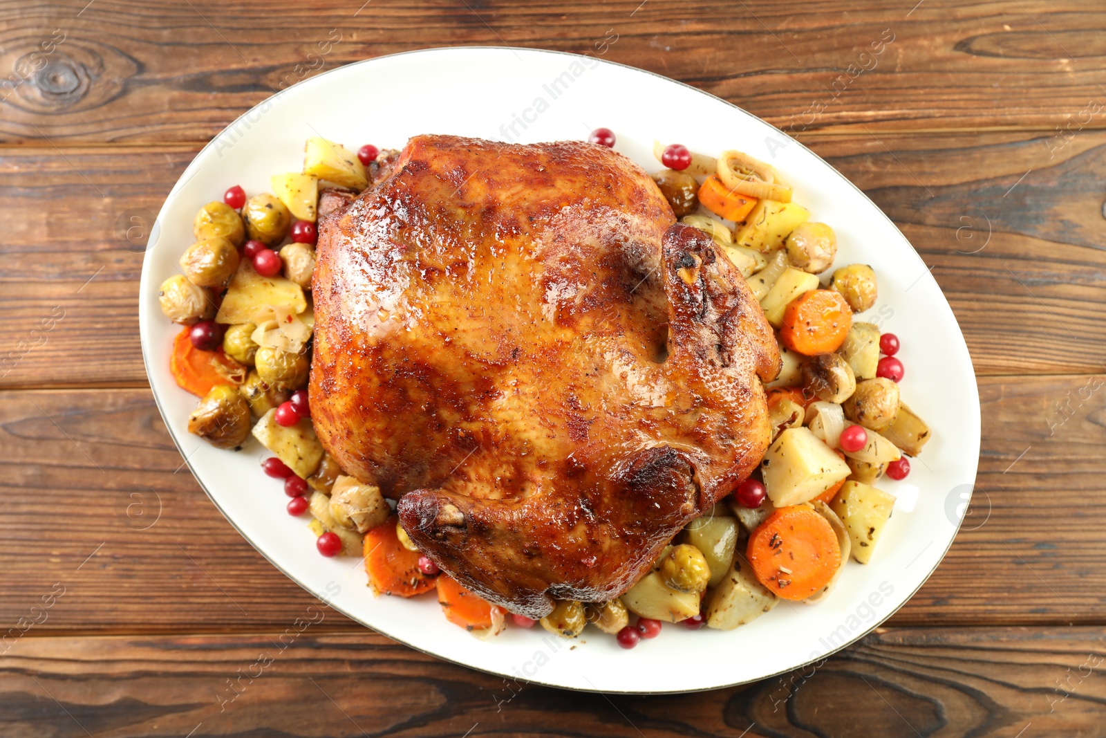 Photo of Delicious baked turkey, vegetables and cranberries on wooden table, top view