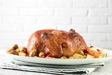 Photo of Delicious baked turkey, vegetables and cranberries on gray textured table against white brick wall closeup