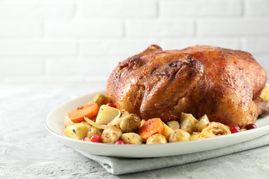 Photo of Delicious baked turkey, vegetables and cranberries on gray textured table against white brick wall, closeup