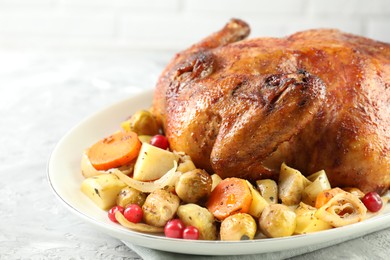 Photo of Delicious baked turkey, vegetables and cranberries on gray textured table, closeup