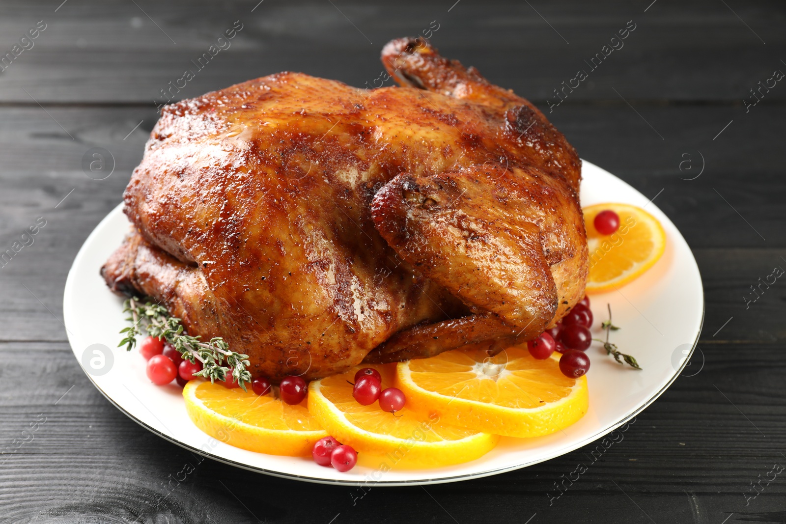 Photo of Delicious baked turkey, orange slices, cranberries and thyme on gray wooden table, closeup