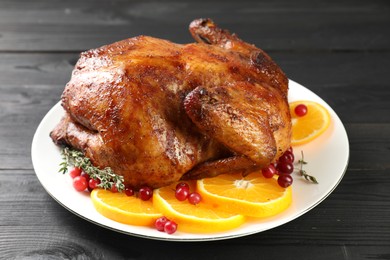 Photo of Delicious baked turkey, orange slices, cranberries and thyme on gray wooden table, closeup