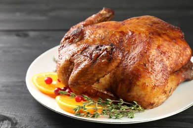 Photo of Delicious baked turkey, orange slices, cranberries and thyme on gray wooden table, closeup