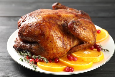 Photo of Delicious baked turkey, orange slices, cranberries and thyme on gray wooden table, closeup