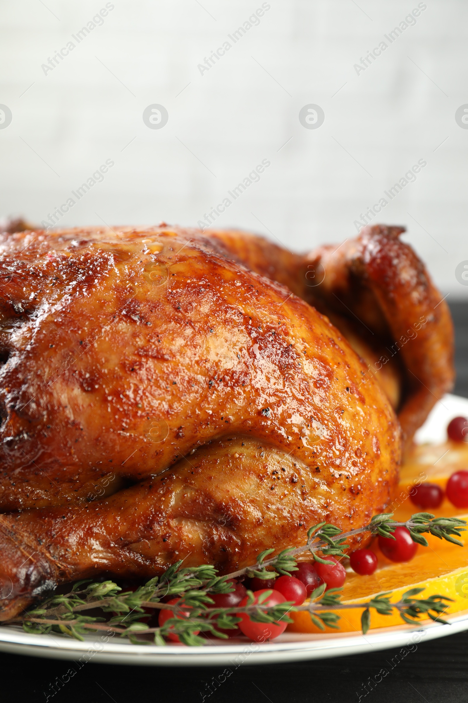 Photo of Delicious baked turkey, orange slices, cranberries and thyme on table, closeup