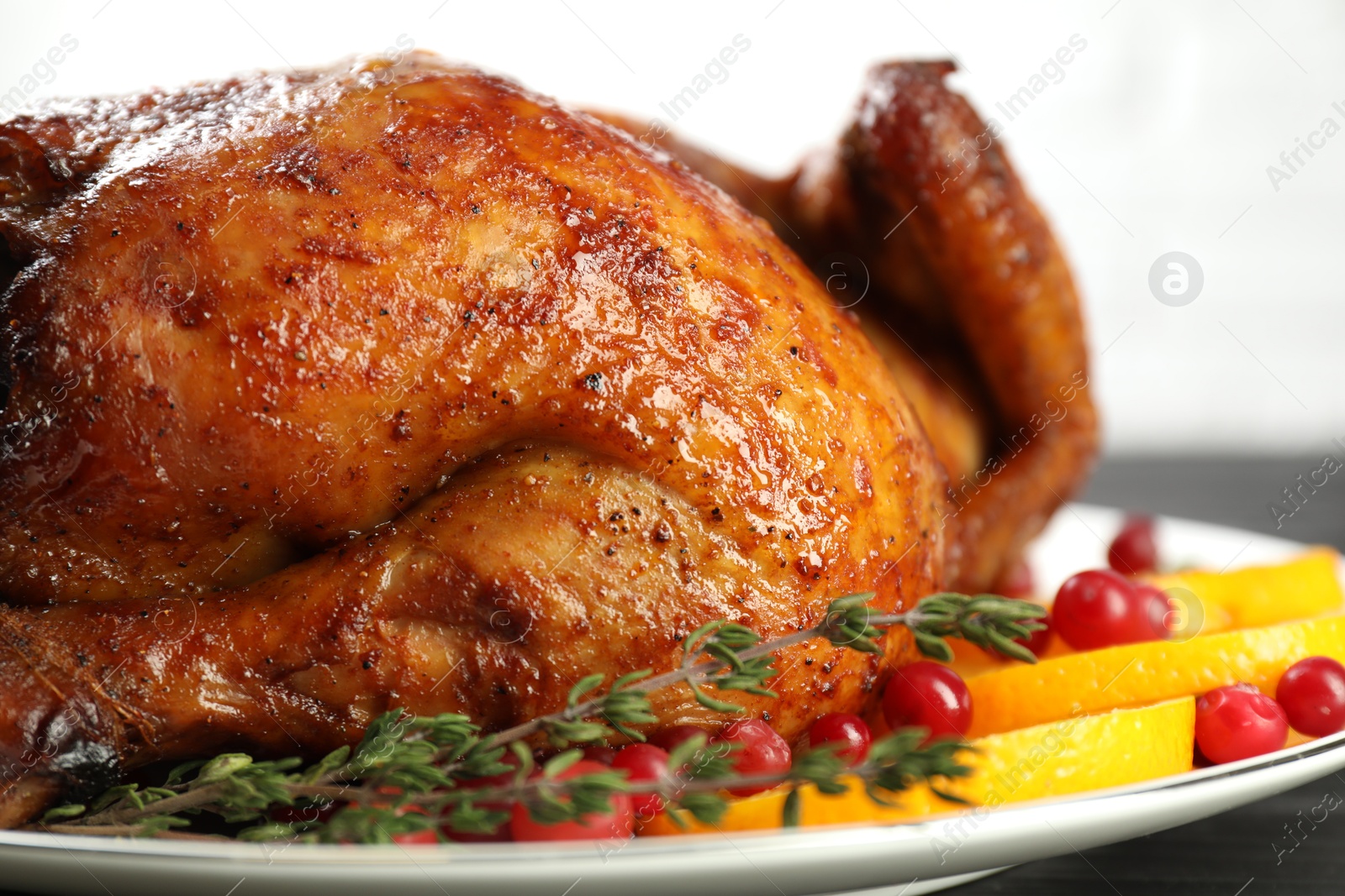 Photo of Delicious baked turkey, orange slices, cranberries and thyme on table, closeup