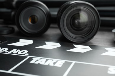 Photo of Movie clapper and camera lens on table, closeup