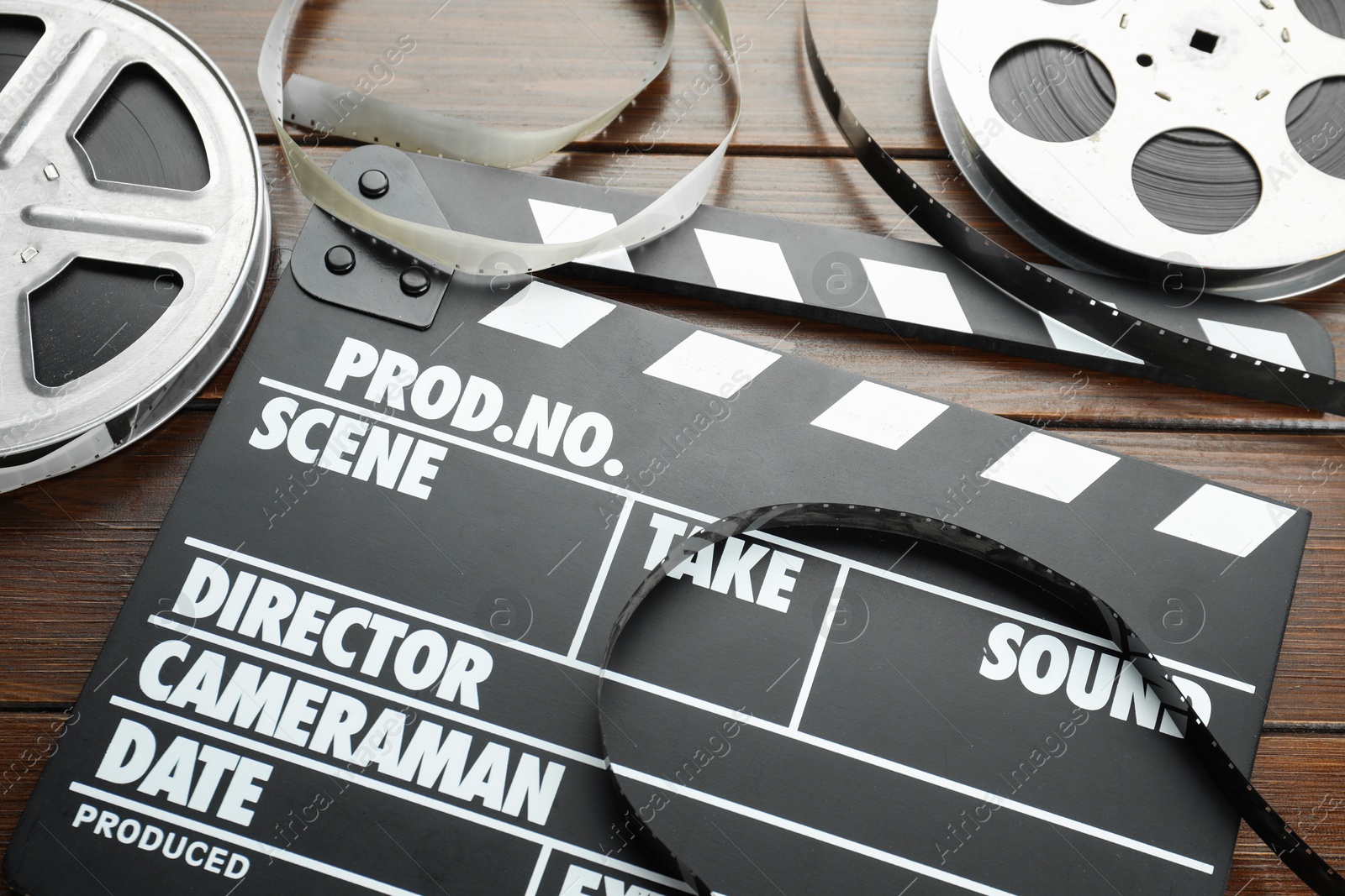 Photo of Movie clapper and film reels on wooden table, above view