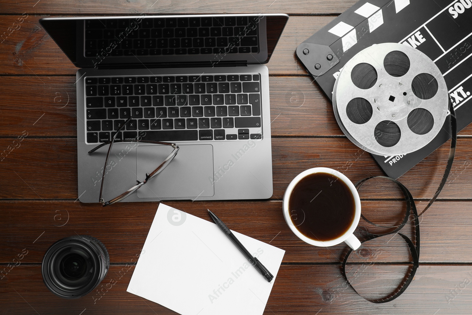 Photo of Flat lay composition with movie clapper, film reel and laptop on wooden table