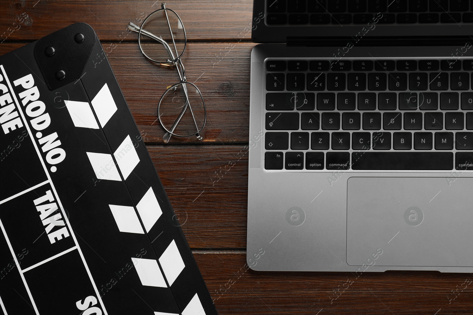 Photo of Movie clapper, glasses and laptop on wooden table, flat lay