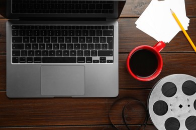 Photo of Flat lay composition with film reel and laptop on wooden table