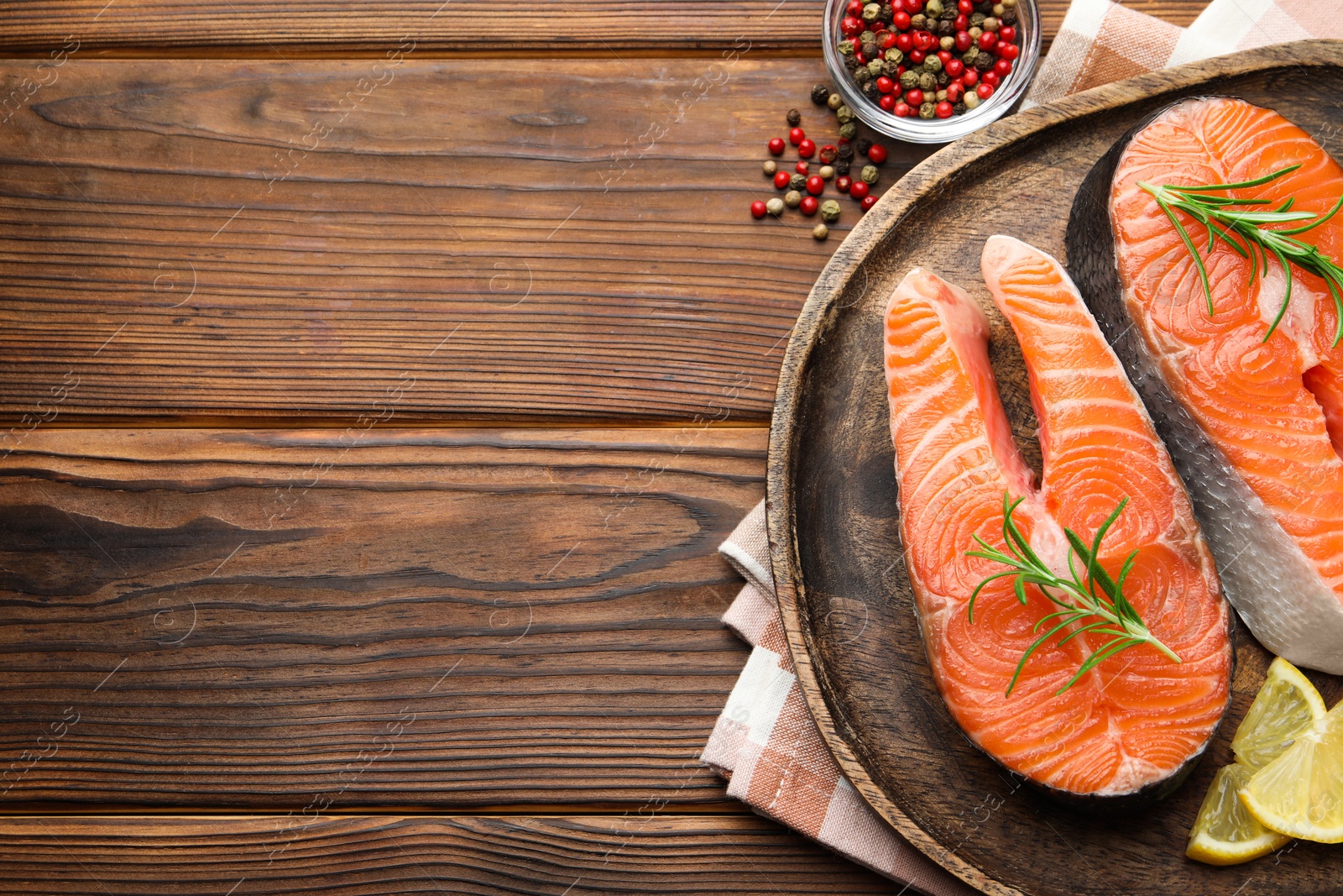 Photo of Fresh raw salmon steaks and spices on wooden table, flat lay. Space for text