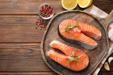 Photo of Fresh raw salmon steaks and spices on wooden table, flat lay. Space for text