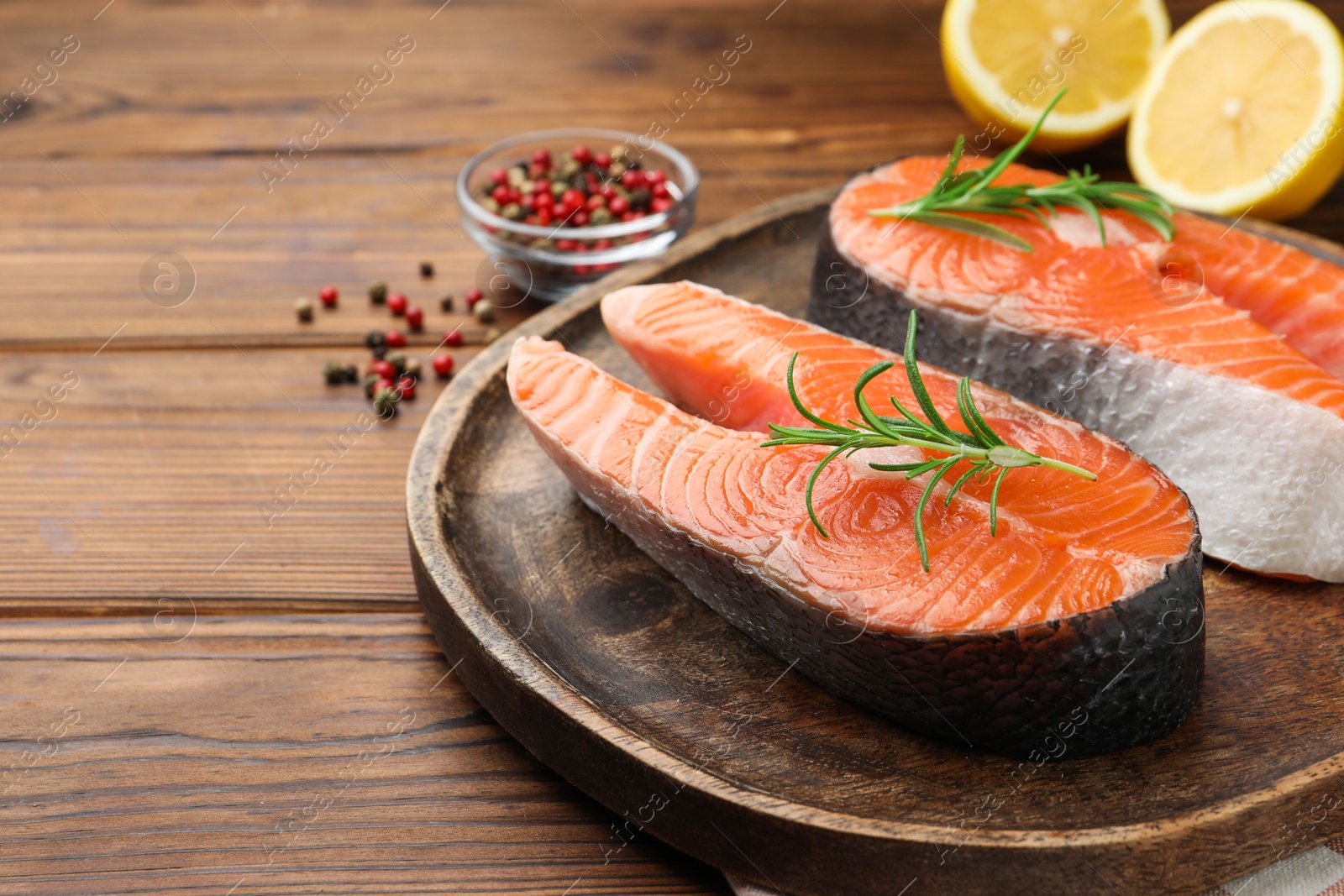 Photo of Fresh raw salmon steaks and spices on wooden table, closeup