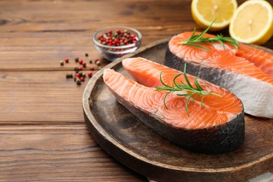 Photo of Fresh raw salmon steaks and spices on wooden table, closeup