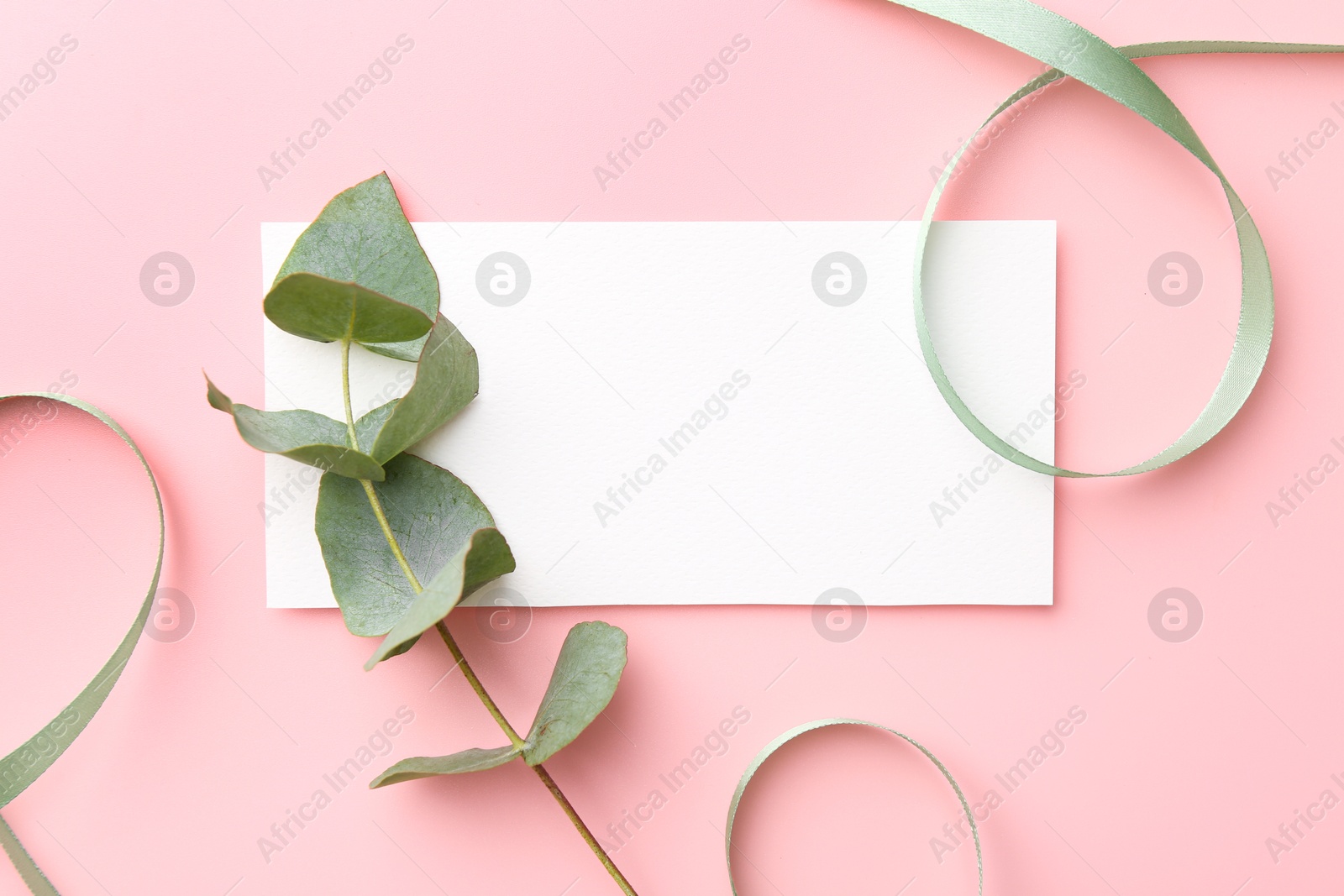 Photo of Blank card, ribbons and eucalyptus branch on pink background, flat lay