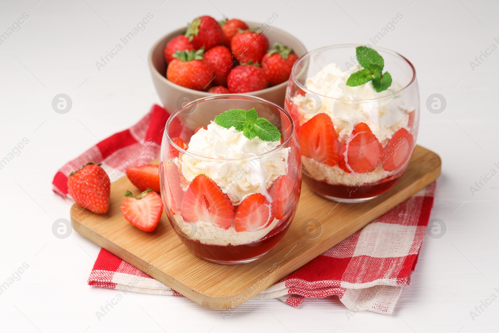 Photo of Tasty trifle dessert. Sponge cake, strawberries, jam and whipped cream on white wooden table, closeup