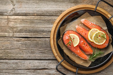 Photo of Fresh raw salmon steaks with spices in pan on wooden table, top view. Space for text