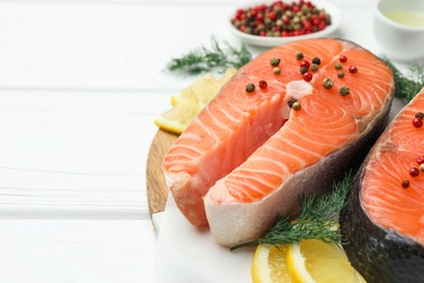 Photo of Fresh raw salmon steaks with peppercorns, lemon and dill on white wooden table, closeup. Space for text